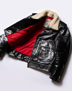 The Dawson glossy black leather motorcycle jacket shown open, revealing the bright red quilted interior lining. The jacket features a cream shearling collar and silver zippers.