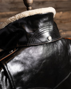 Close-up of a black leather jacket with shearling lining on a wooden background