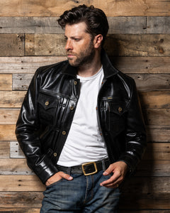 Man wearing a black leather jacket, white shirt, and blue jeans against a wooden wall-Master Supply Co - Convoy 25 - Leather Jacket.